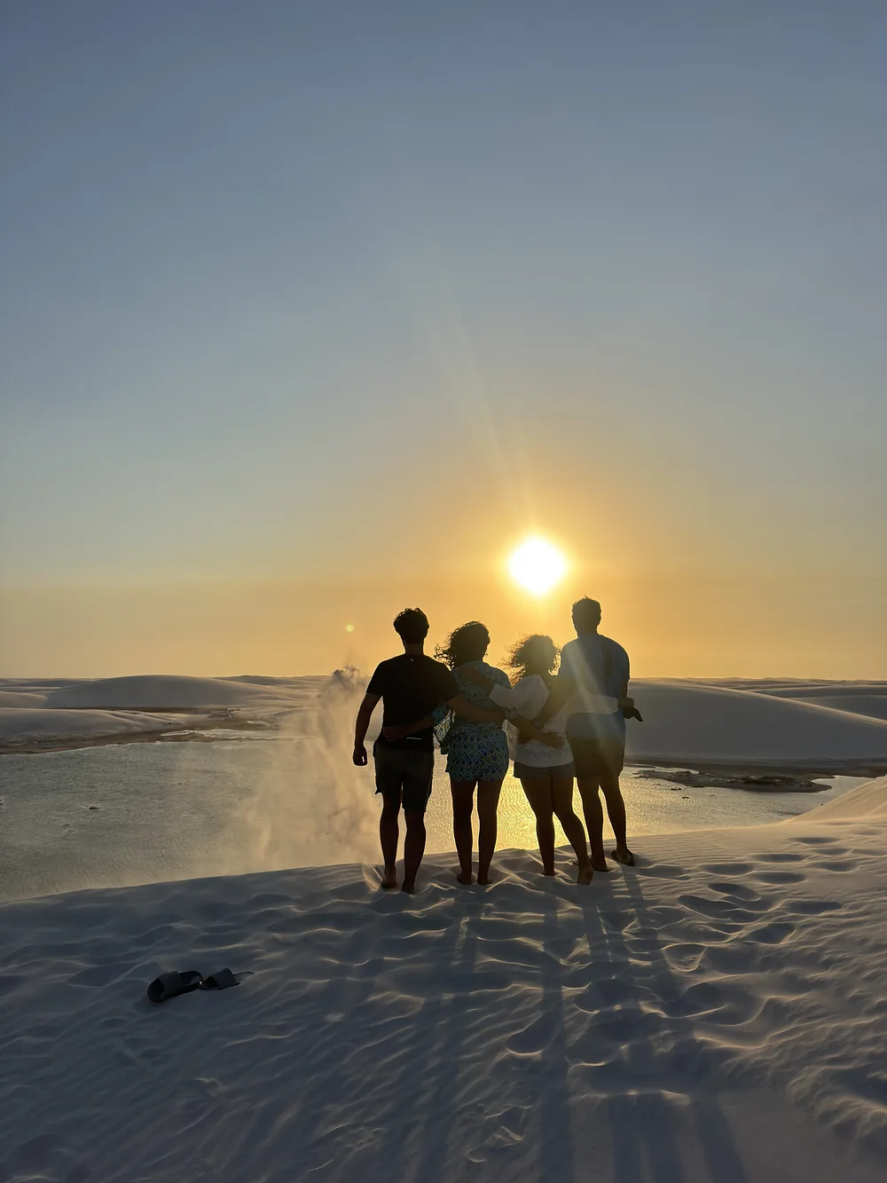 Amigas em silhueta numa duna, ao pôr do sol
